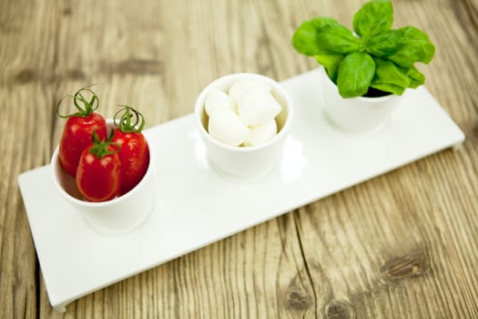 tasty tomatoes mazarella and basil on plate on wooden background