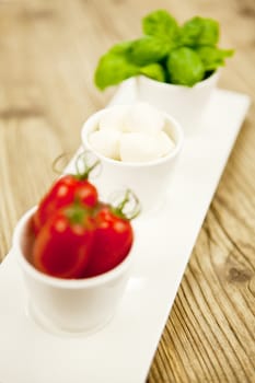tasty tomatoes mazarella and basil on plate on wooden background