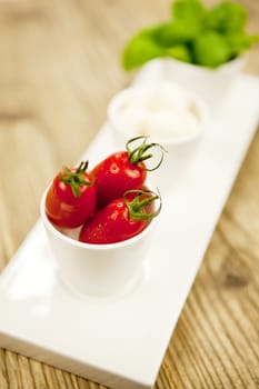 tasty tomatoes mazarella and basil on plate on wooden background