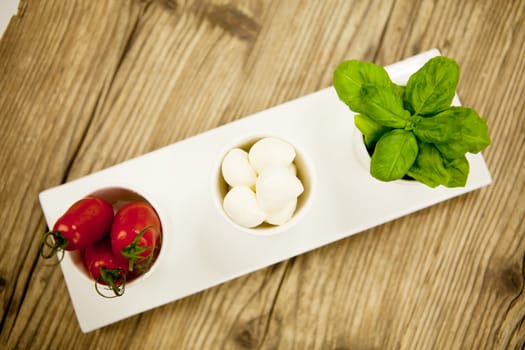 tasty tomatoes mazarella and basil on plate on wooden background
