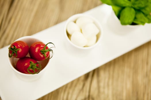 tasty tomatoes mazarella and basil on plate on wooden background