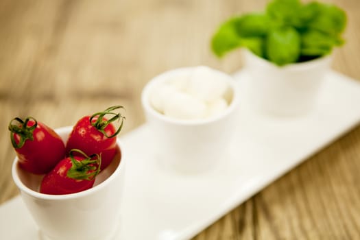 tasty tomatoes mazarella and basil on plate on wooden background