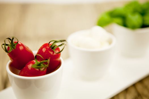 tasty tomatoes mazarella and basil on plate on wooden background