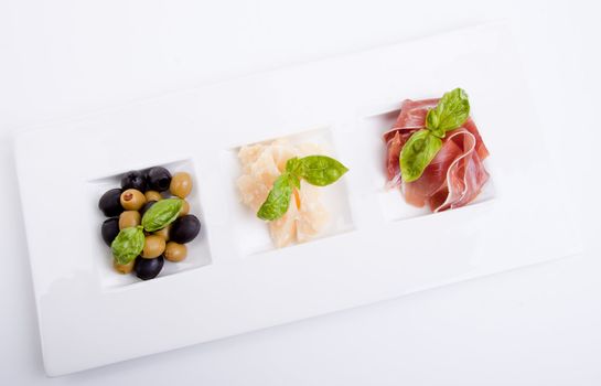 deliscious antipasti plate with parma parmesan and olives isolated on white background