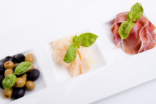 deliscious antipasti plate with parma parmesan and olives isolated on white background