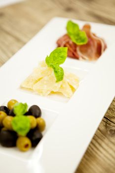 deliscious antipasti plate with parma parmesan olives on wooden background