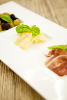 deliscious antipasti plate with parma parmesan olives on wooden background