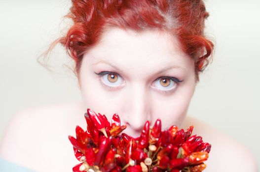 beautiful red hair and lips girl with red chillies on white background