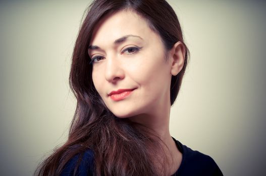 portrait of beautiful girl with long hair and blue sweater on gray background