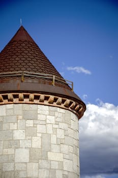 Round castle tower close view with clouds behind.