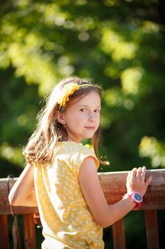 Young girl smiling and standing by a wooden fence