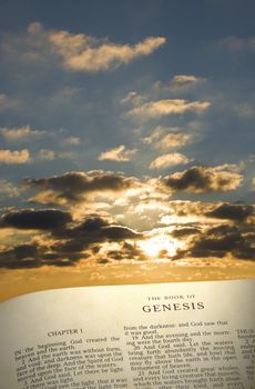 Vertical image of  the Book of Genesis…in the beginning with morning sun and clouds in the background