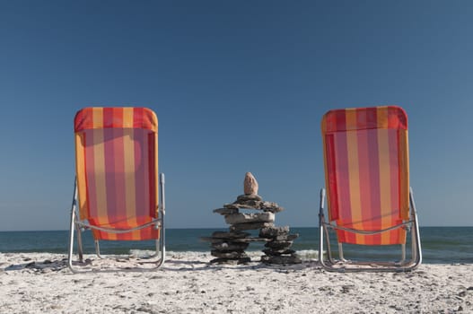 Inudshuk sitting between two lounging chairs resting on the Lake Ontario shoreline