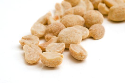 A few peanuts on white background - selective focus on the foreground