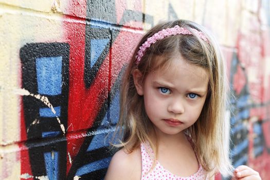 Worried little girl in an urban setting looking into the camera.
