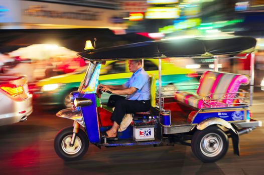 Bangkok, Thailand - March 03, 2013: Tuk - tuk driver riding his tuk-tuk on Chinatown street at night .  There are more than 100,000 "tuk-tuk" in Bangkok.