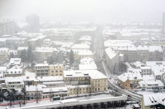 Panoramic view on town with falling snow.