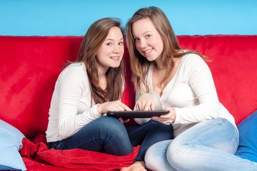 happy teenagers using tablet on the couch at homein the living room