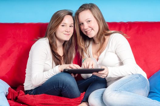 happy teenagers using tablet on the couch at homein the living room