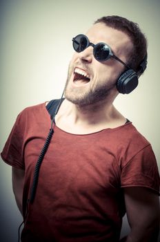 vintage portrait of fashion guy with headphones and sunglasses on gray background