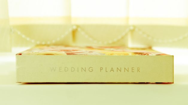 A wedding planner journal on a window sill in light airy colours