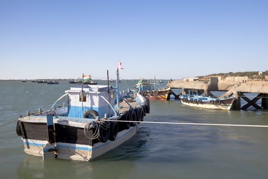 Horizontal capture of fishing boats moored at Bet Dwarka pier late afternoon at Bet Dwarka in Gujarat India