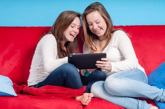 happy teenagers using tablet on the couch at homein the living room