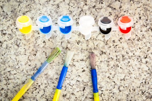 Paint brushes and pots of colorful paint