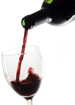 Pouring red wine in glass with white background.