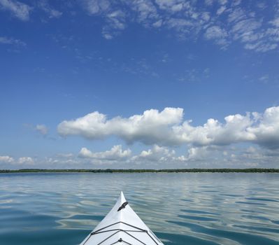 Kayak on the lake with copy space in the blue sky with large clouds on the horizon