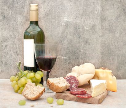 Glass of red wine with different cheese and cold meat on a chopping board 