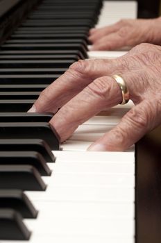 Selective focus on the foreground hand of an older man playing the piano