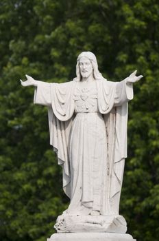 Selective focus on the marble statue of Jesus Christ with tree in the background
