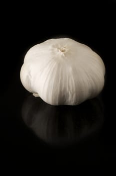 Garlic clove on black background with slight reflection on the tile