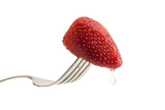 Strawberry on a fork and falling droplet of water with a white background