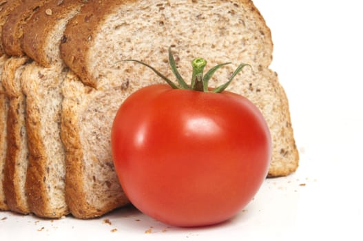 Selective focus on single tomato with fresh whole wheat bread in the background