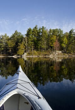 Kayak on a tranquil northern lake with reflection of a wilderness island in the foreground