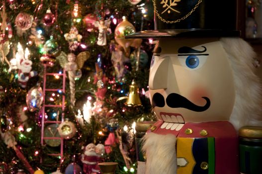 Selective focus on the Nutcracker guarding the Christmas tree.