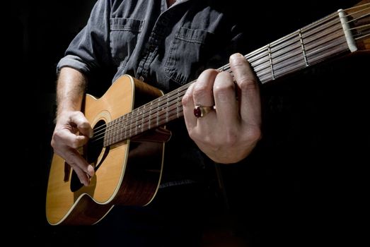 High contrast photo of a musician playing an acoustic guitar.