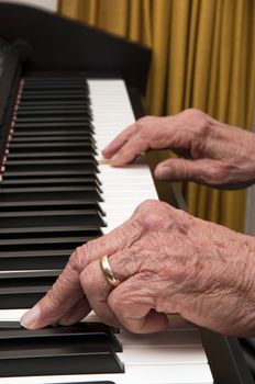 Selective focus on old hands playing the piano 