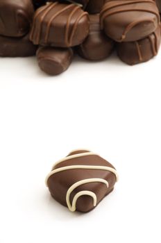 Vertical image with selective focus on the single chocolate in the foreground with multiple chocolates in the background