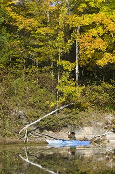 Woman taking photos along the shoreline of a northern lake from her kayak