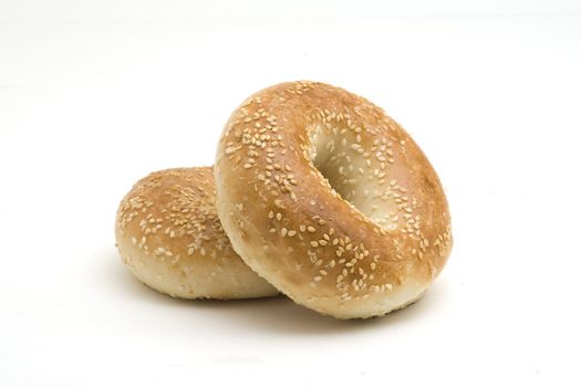 Two sesame seed bagels on a white background
