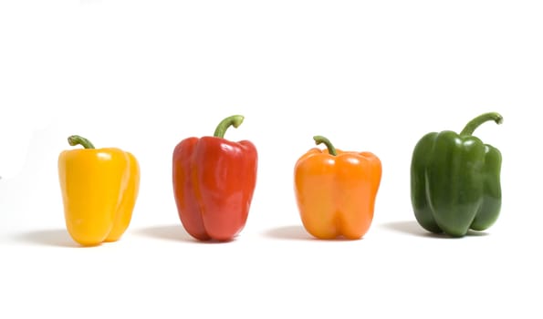 A row of multi colored bell peppers isolated on white background.