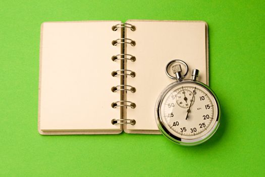Notepad and stopwatch isolated on green background