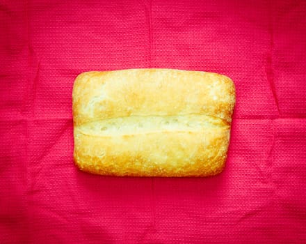 A lovely freshly baked loaf of bread on a pink cloth