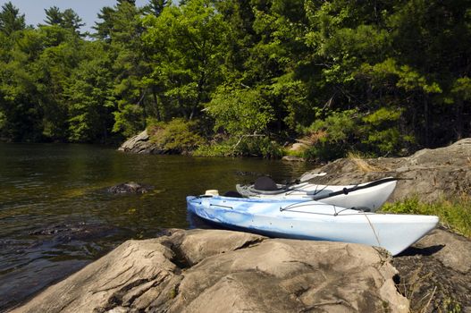 Two kayaks on the rocky shoreline of a northern lake