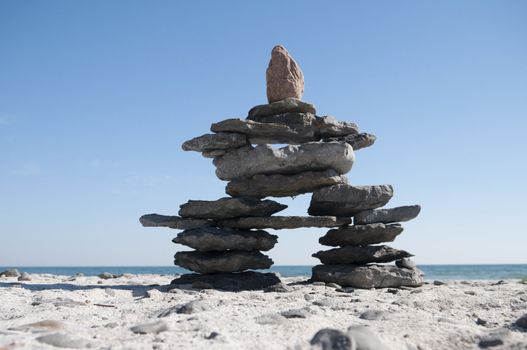 Inukshuk resting on the shoreline with blue sky copy space area