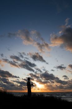Silhouette of a person walking along the shoreline at sunset in Nova Scotia