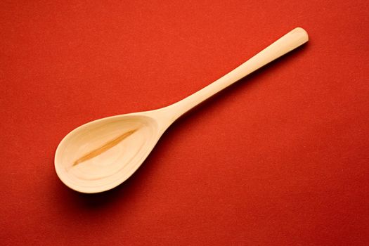Wooden spoon isolated on red background